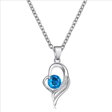 Load image into Gallery viewer, Silver necklace with a blue crystal pendant in a heart-shaped setting.
