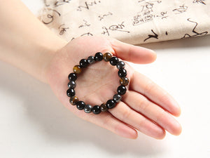 Beaded bracelet featuring hematite, tiger's eye, and obsidian stones on a hand.